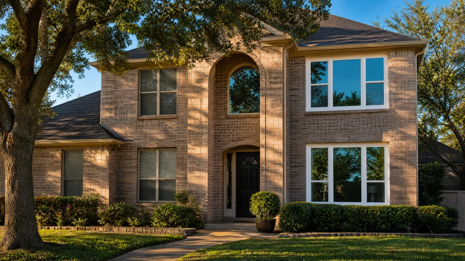 Exterior view of an older brick home with half the windows replaced with new energy-efficient glass